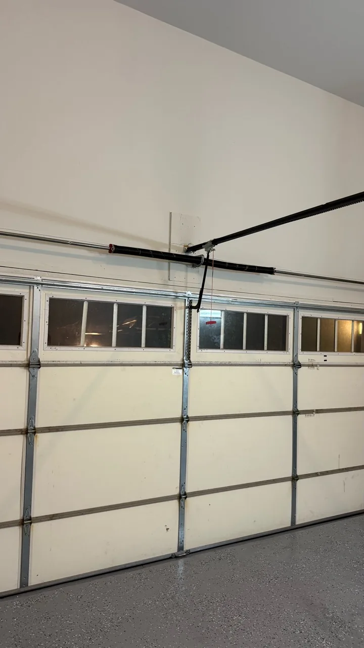 Interior of a white sectional garage door with torsion springs and an opener rail above it