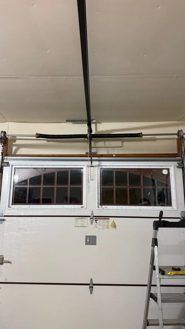 Two torsion springs above a white garage door with decorative windows