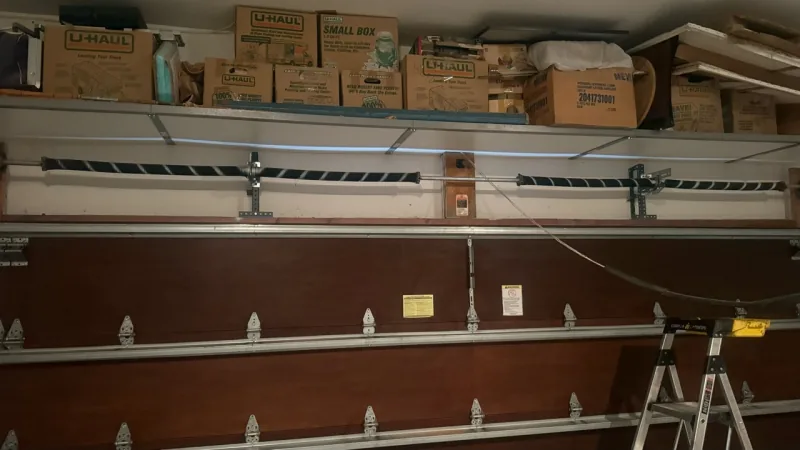 Interior of a brown wood garage door with torsion springs and hardware above it