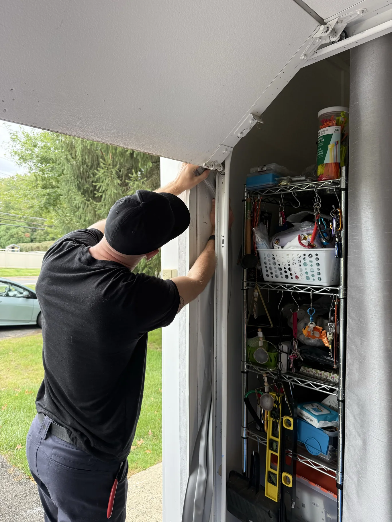 Literally Garage Door technician working on weatherstripping beside a sectional garage door